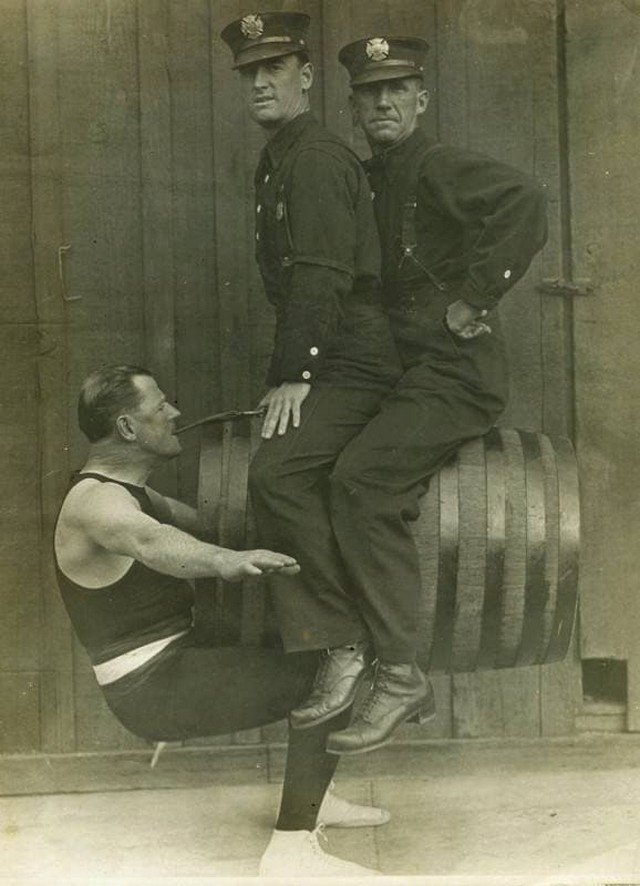 Гарри Ф. Гриффин, силач из пожарной охраны Лос-Анджелеса, держит зубами двух коллег, 1914 год.